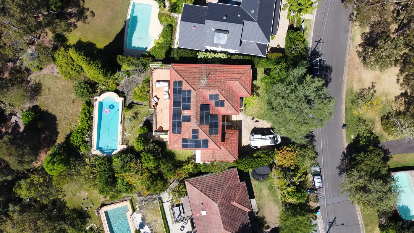 Solar panels on a terracotta tile roof beside a pool